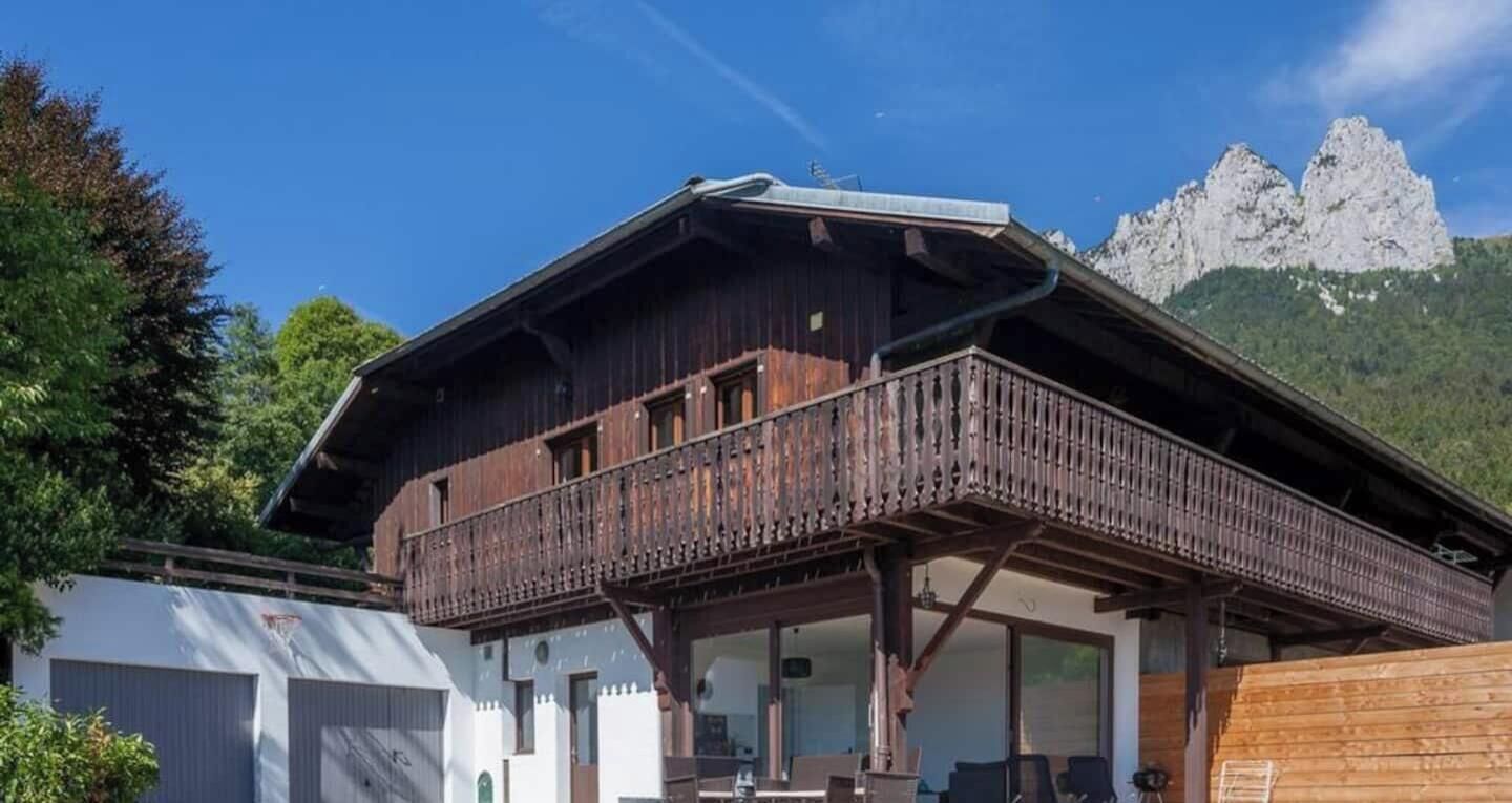 Un bâtiment de style chalet, doté d’un balcon, de grandes fenêtres et surplombant un paysage montagneux.