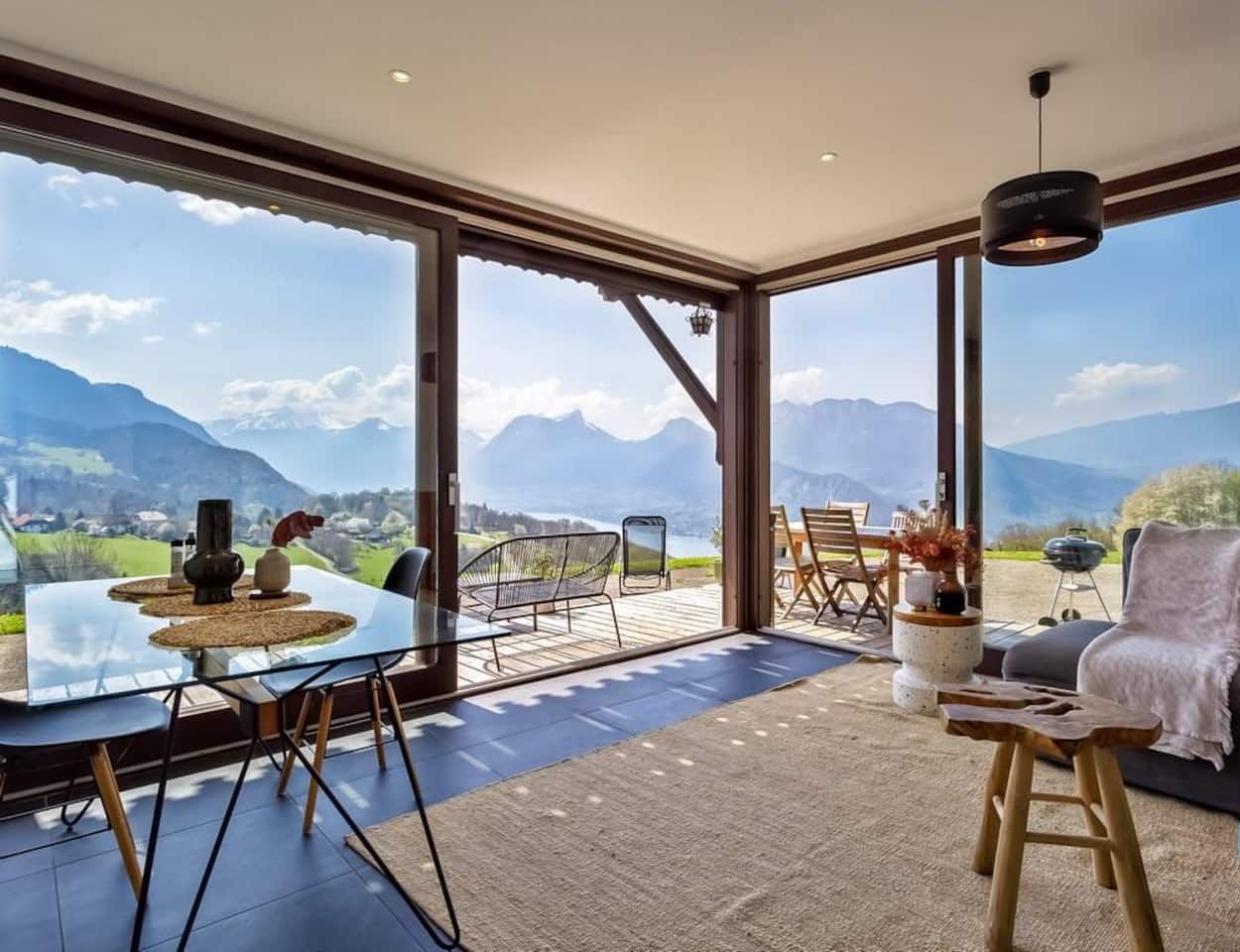 A modern interior with large windows, a dining area, and a seating space with a view of mountains.