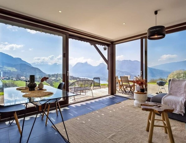 Un interior moderno con ventanas amplias, una zona de comedor y un espacio de estar con vistas a las montañas.
