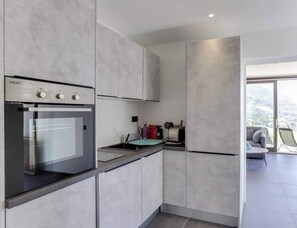 Una cocina moderna con horno empotrado y vistas a un balcón con sofá y sillones.