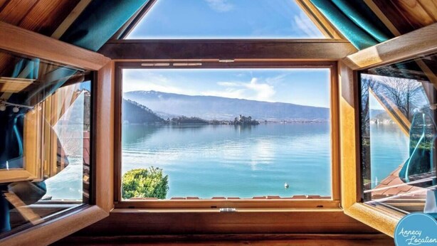 Une pièce dotée d’une grande verrière donnant sur un lac et des montagnes.