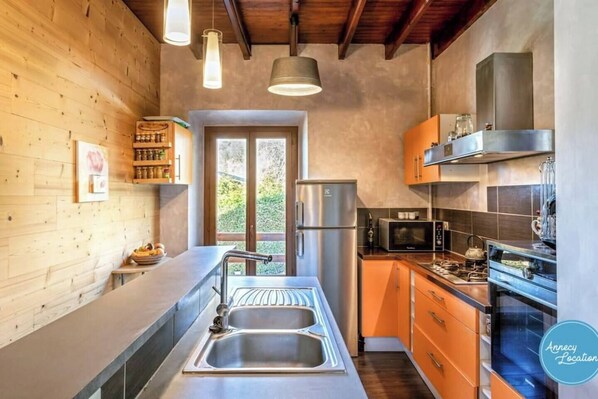 A modern kitchen with wooden walls, stainless steel appliances, and a large window.