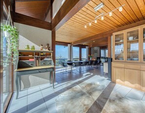 A spacious kitchen with wooden cabinets, a dining area with chairs, and a large window offering a view. - La Sauffaz- Villa with a pool. (Talloires-Montmin)