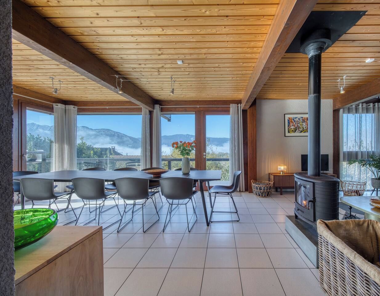 A spacious room with a large dining table, chairs, a fireplace, and a view of the mountains.