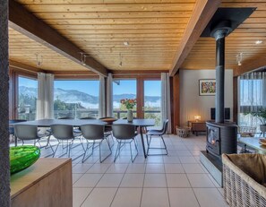 A spacious room with a large dining table, chairs, a fireplace, and a view of the mountains. - La Sauffaz- Villa with a pool. (Talloires-Montmin)