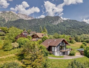 A mountain village with traditional wooden houses, a central modern house with a balcony, and a clear view of the surrounding mountains. - La Sauffaz- Villa with a pool. (Talloires-Montmin)