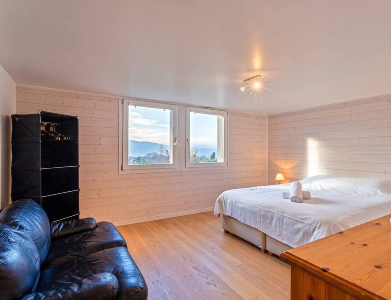 Una stanza con un letto, una scrivania in legno, un divano in pelle e un mobile contenitore nero.