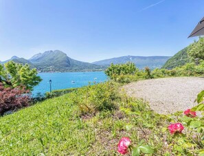 Une vue pittoresque d’un lac, avec des montagnes en arrière-plan, un sentier de gravier et un belvédère abritant une table et des chaises.