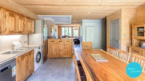 Eine Küche mit Holzausstattung, einer zentralen Kochinsel und einem Essbereich mit einem Holztisch und Bänken.