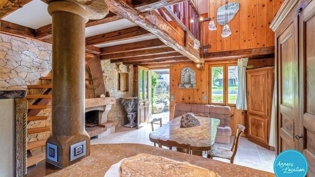 Ein rustikales Interieur mit Kamin aus Stein, Holzbalken und einer Steinwand.