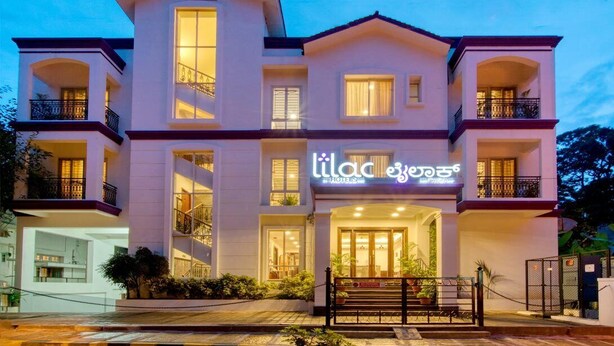 A multi-story hotel with a prominent entrance, balconies, and a well-lit facade. - Lilac by Tamara 3rd Block Jayanagar (Bengaluru)