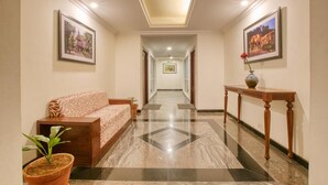 A hotel hallway with a sofa, a console table, and framed pictures on the walls. - Lilac by Tamara 3rd Block Jayanagar (Bengaluru)