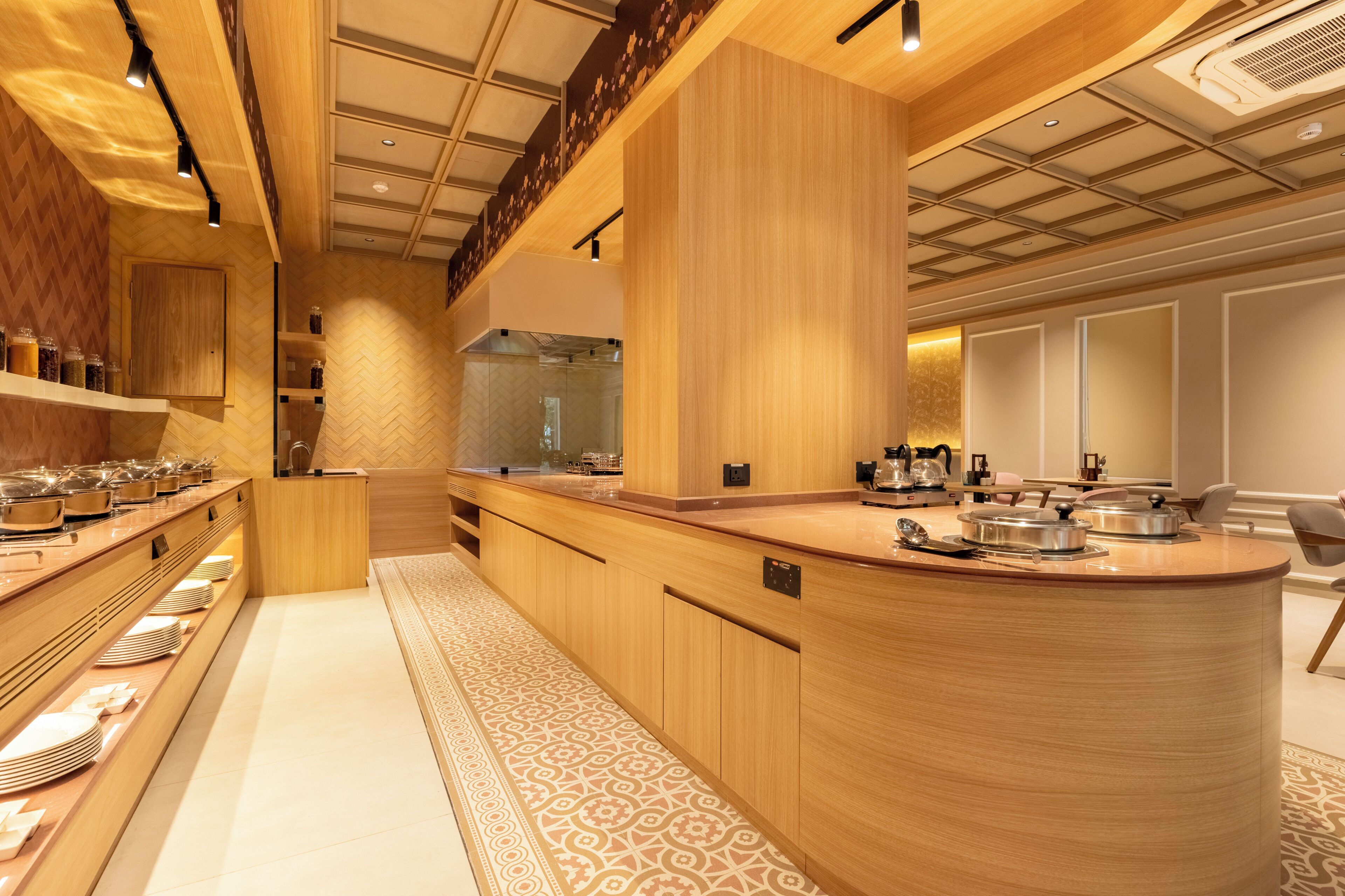 A modern kitchen with a central island, wooden cabinetry, and a herringbone-patterned floor.
