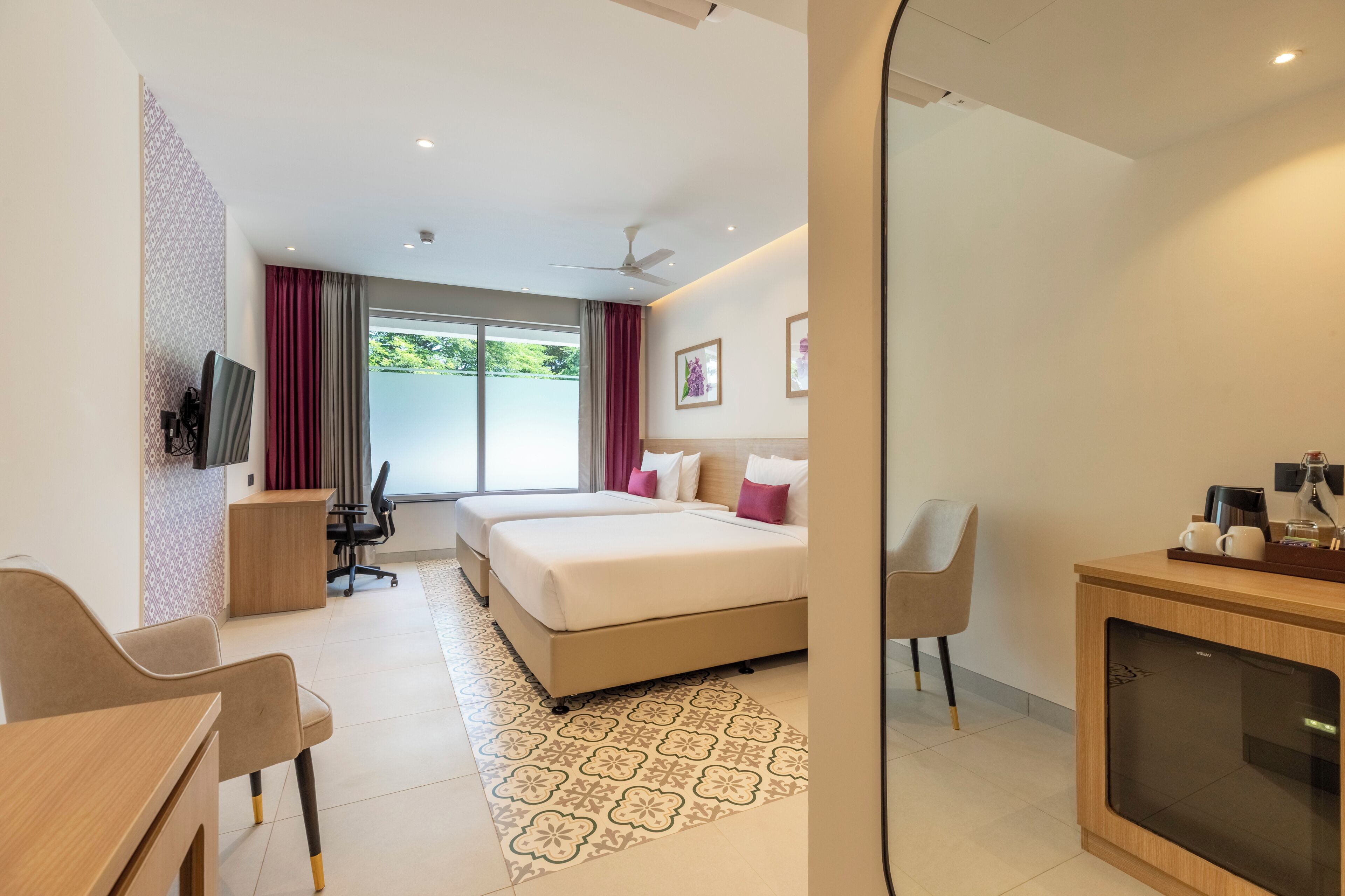 Een hotelkamer met een bed, bureau, stoel en een aan de muur bevestigde televisie.