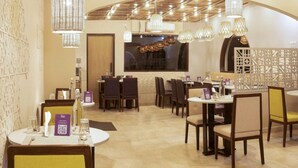 A restaurant with round tables, chairs, and hanging pendant lights. - Lilac by Tamara 3rd Block Jayanagar (Bengaluru)