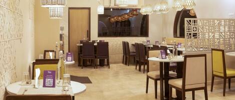 A restaurant with round tables, chairs, and hanging pendant lights.