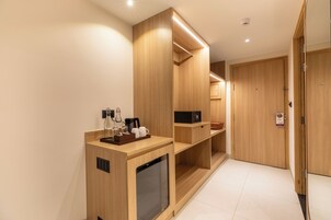 A modern hotel room with a wooden vanity, a microwave, and a small refrigerator.