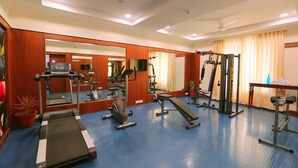 A gym with exercise equipment, mirrors, and a blue floor. - Lilac by Tamara 3rd Block Jayanagar (Bengaluru)