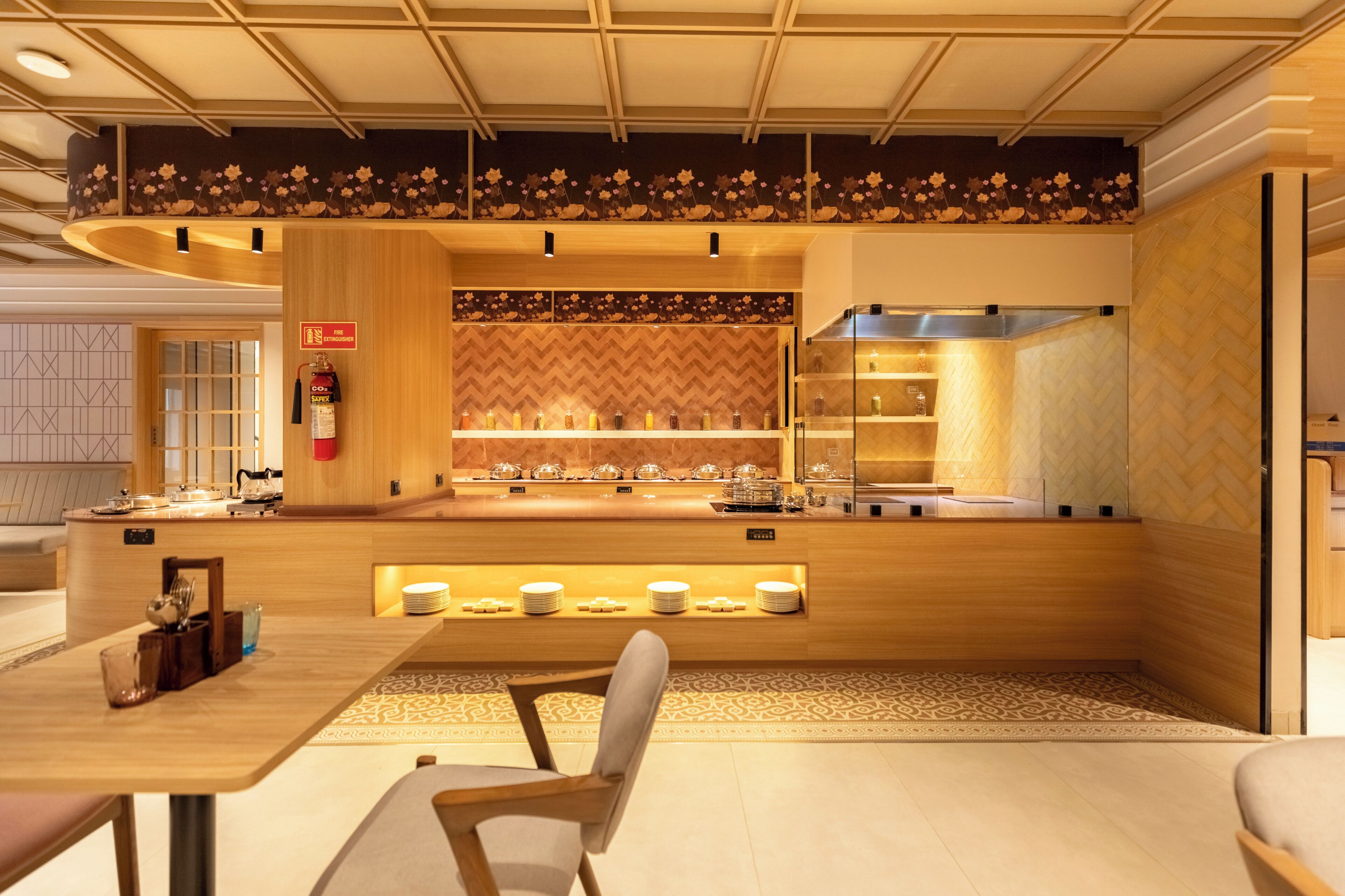 A modern restaurant with a wooden interior, a fire extinguisher sign, and a buffet area with various dishes.