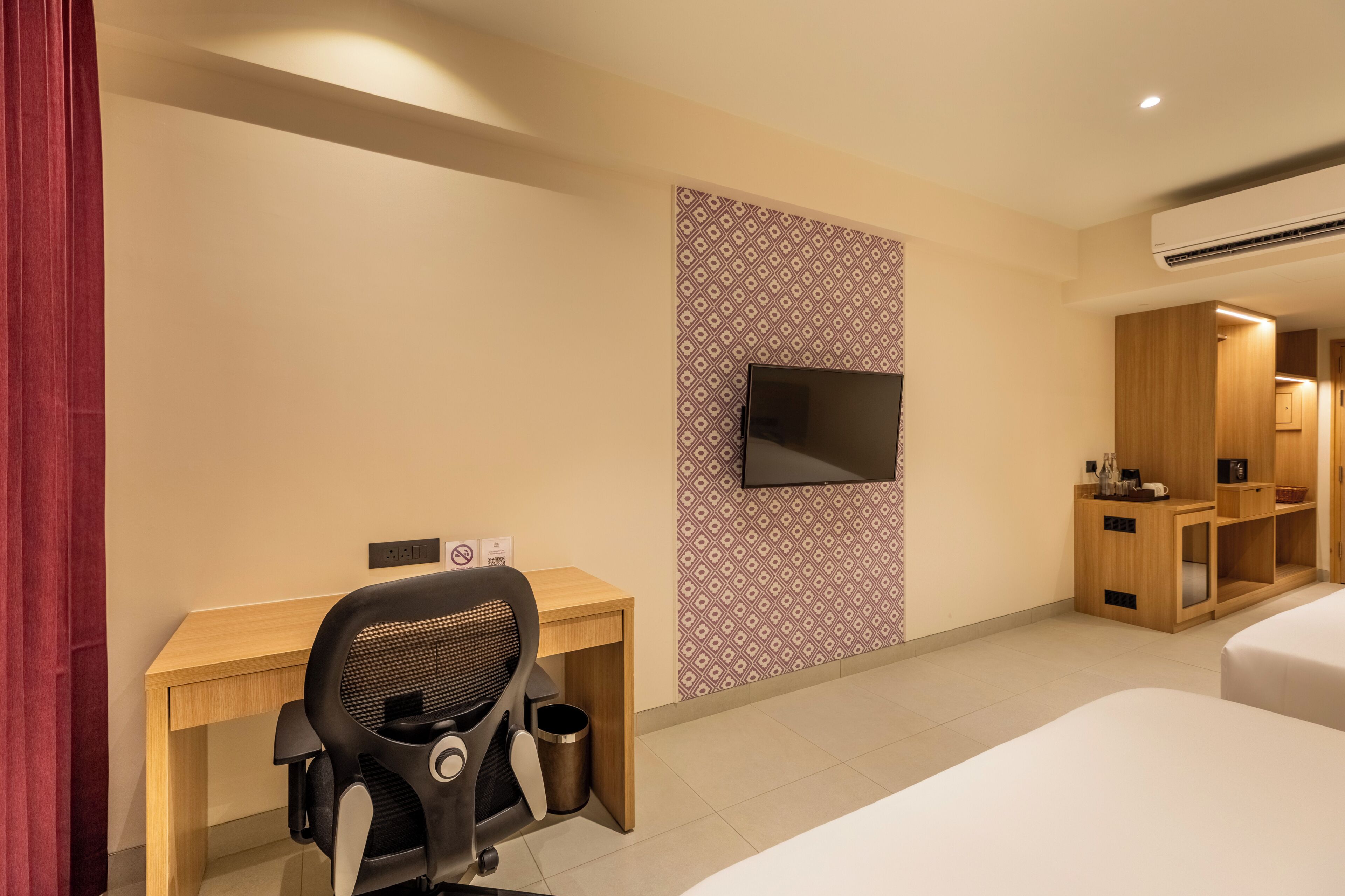 Une chambre d’hôtel équipée d’un lit, d’un bureau, d’une chaise, d’un téléviseur fixé au mur et d’une armoire.
