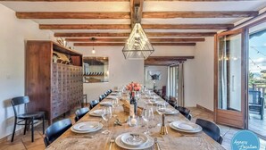 A dining area with a long wooden table set for a meal, flanked by black chairs, and a wooden cabinet with drawers.