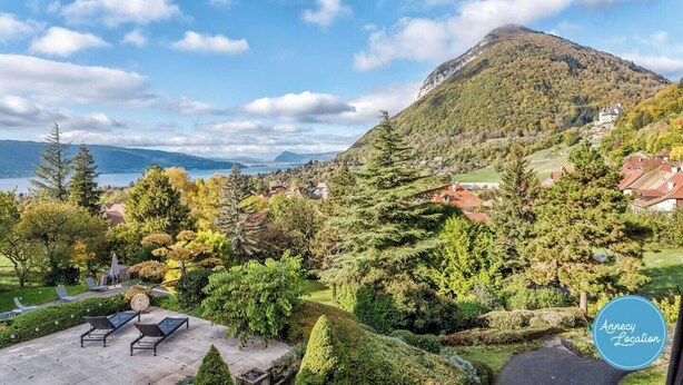 A mountainous landscape with a lake, a village, and a garden with seating.