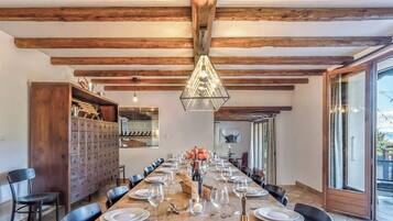 A dining area with a long wooden table set for a meal, flanked by black chairs, and a wooden cabinet with drawers.