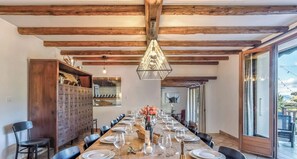 A dining area with a long wooden table set for a meal, flanked by black chairs, and a wooden cabinet with drawers. - Les Coteaux - Family house with lake view. (Menthon-Saint-Bernard)
