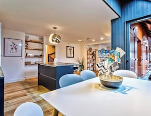 A modern kitchen with a central island, a dining area with a white table, and a blue accent wall. - Magnificent Apartment T3 - Near the lake of Annecy (Menthon-Saint-Bernard)