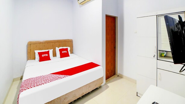 A bedroom with a bed, a wardrobe, and an air conditioning unit.