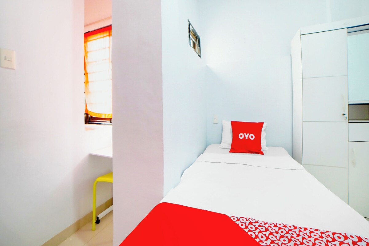 Un dormitorio pequeño y ordenado con cama, armario y una silla.