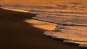 A beach with waves at sunset.
