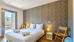 A modern hotel room with a large bed, wooden floor, and a textured wall. - T4 Terre EO - close to Lake Annecy. (Menthon-Saint-Bernard)
