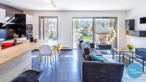 A modern kitchen with a built-in oven and a dining area with a round table and chairs. - T4 Terre EO - close to Lake Annecy. (Menthon-Saint-Bernard)