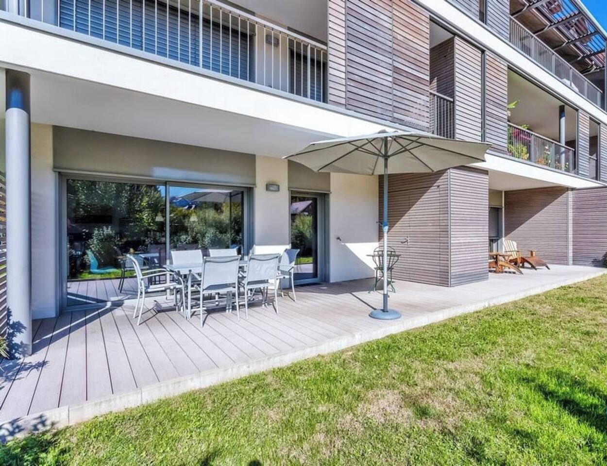 Un appartement moderne doté d’un patio extérieur couvert, d’une piscine et d’une pelouse bien entretenue.