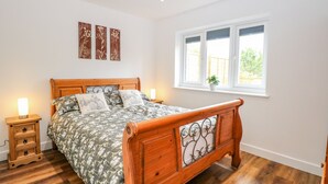 Un dormitorio con cama de madera, mesitas de noche, una ventana con vistas y decoración en la pared.