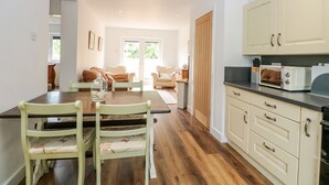 Una cocina moderna con armarios de madera, una mesa de comedor con sillas y vistas al exterior.