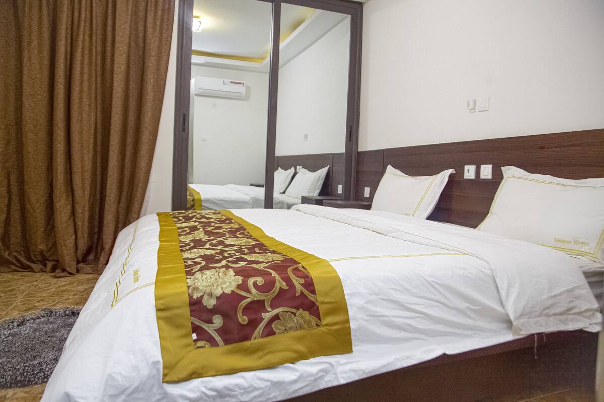 A hotel room with a large bed, a wooden headboard, and a mirror on the wall.