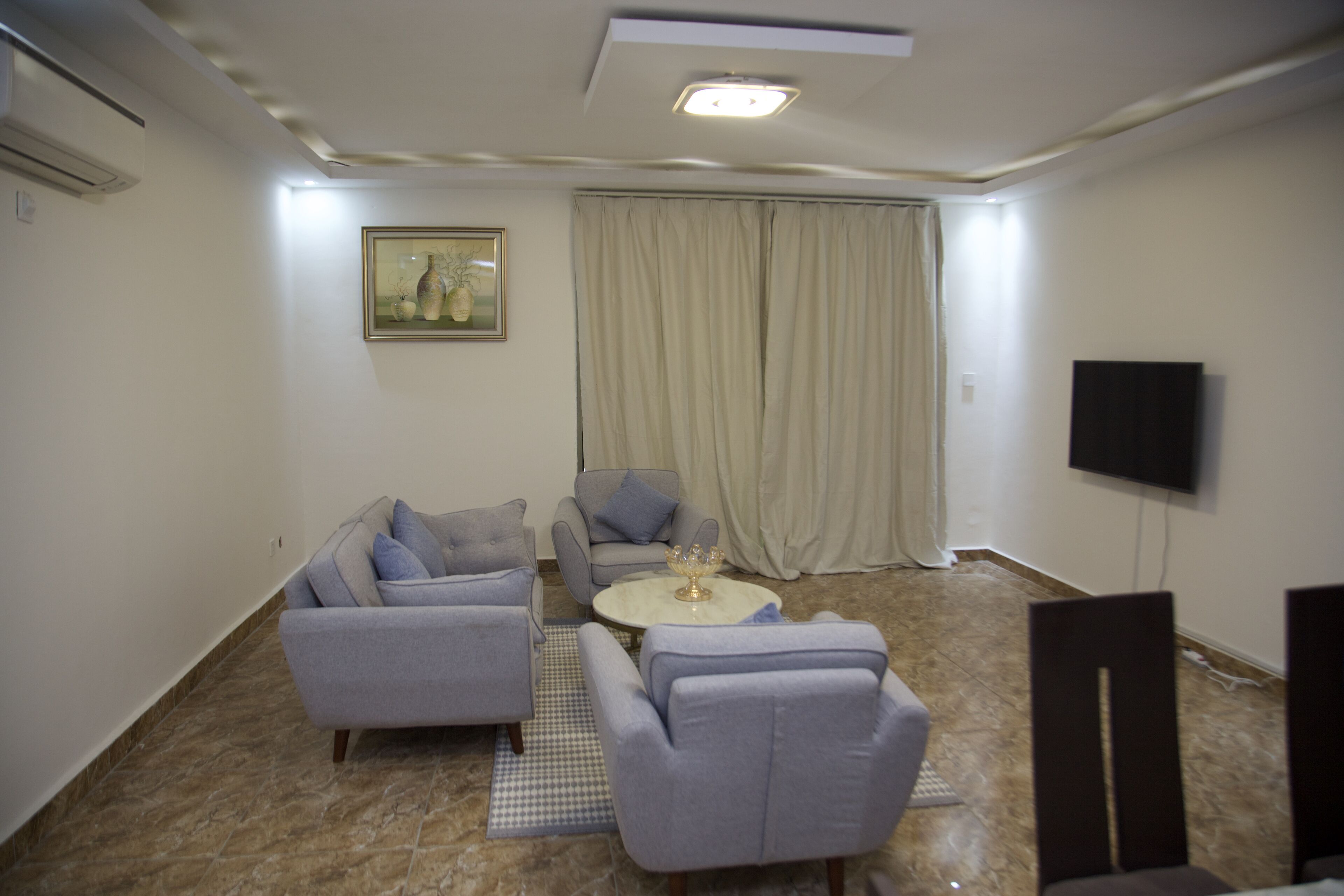 A living room with a sofa set, a coffee table, a TV, and a painting on the wall.