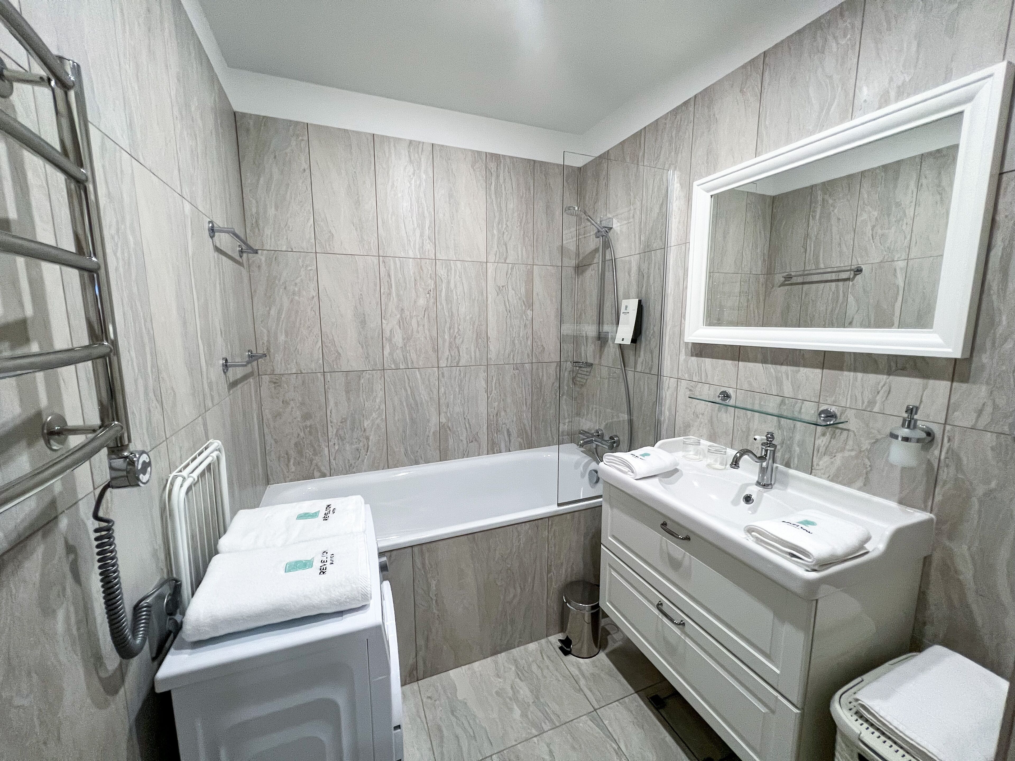 Un baño moderno con bañera, lavamanos con espejo e inodoro.