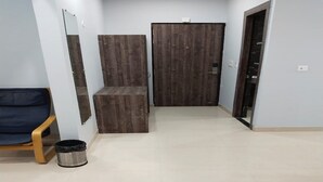 Une pièce spacieuse avec une grande porte en bois, un banc et une poubelle.