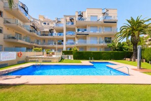 Un immeuble résidentiel à plusieurs étages doté d’une piscine, de balcons et d’une pelouse bien entretenue.