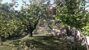 A garden with a table and chairs, surrounded by trees and a stone wall. - Refugi per Boletaires i Amants de la Natura (La Nou de Berguedà)