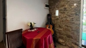 A dining area with a red tablecloth, a guitar, and a stone wall. - Refugi per Boletaires i Amants de la Natura (La Nou de Berguedà)