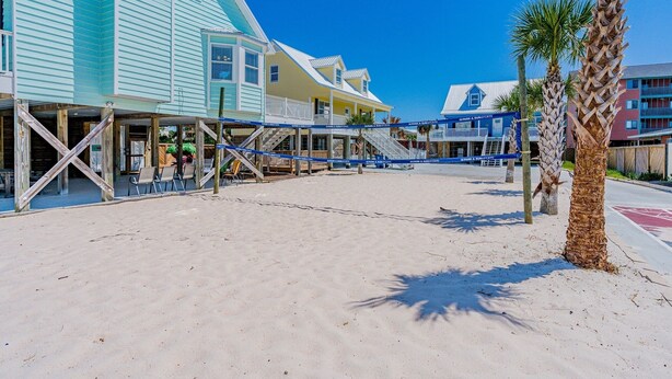 Un hotel frente a la playa con una playa de arena, estructuras de madera y palmeras.