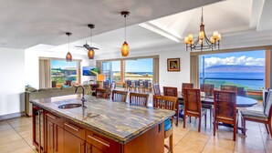 A spacious kitchen with a large island, dining area with wooden chairs, and a view of the ocean. - Combo Units: Konea 1019 & Konea 1026~ 2 Outstanding Units ~ sleeps up to 14 (kaanapali)