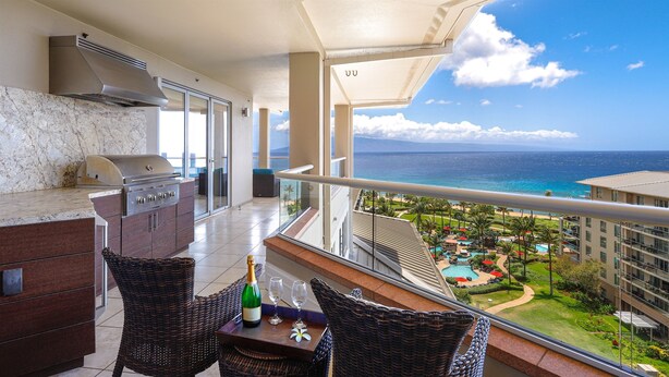 A balcony with a grill, wicker chairs, and a table with a bottle and glasses. - Combo Units: Konea 1019 & Konea 1026~ 2 Outstanding Units ~ sleeps up to 14 (kaanapali)