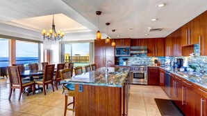 A modern kitchen with wooden cabinets, a large island, and a view of the ocean. - Combo Units: Konea 1019 & Konea 1026~ 2 Outstanding Units ~ sleeps up to 14 (kaanapali)