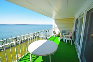 A balcony with a table and chairs, overlooking a body of water.