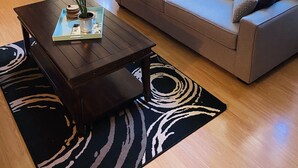 A living room with a sofa, coffee table, and a view of the outdoors. - KingBed,Sleeps10+,SmrtTV,BBQ,Gym,FireTable,FullKitchen. All in walking distance. (Goderich)